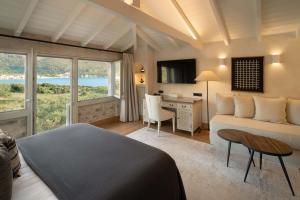 a bedroom with a bed and a table and a desk at Porto Vitilo Boutique Hotel in Karavostasi