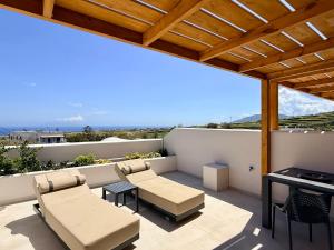 a patio with chairs and a table on a balcony at Nohēme Luxury Suites in Vourvoúlos