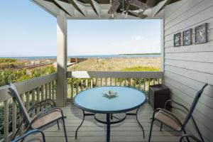 a table and chairs on a porch with a view of the ocean at 1305 Pelican Watch Villa in Seabrook Island