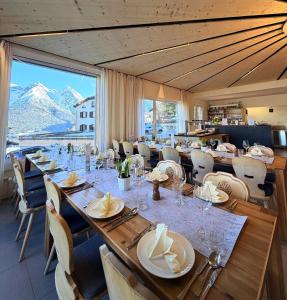 a dining room with a long table with chairs and a large window at Hotel Bellavista Ftan in Ftan