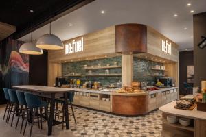 a restaurant with a counter with chairs and a table at Aloft by Marriott Belfast Titanic Quarter in Belfast