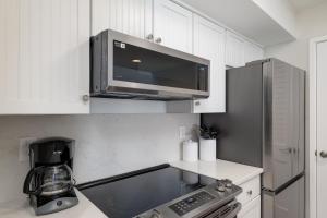a kitchen with white cabinets and a black microwave at 1306 Pelican Watch Villa in Seabrook Island