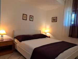 a bedroom with a bed with two lamps and a window at Apartments Rose in Stanići +53 photos