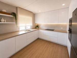 a kitchen with white cabinets and a wooden floor at Waves beach house in Viana do Castelo