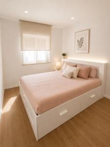 a white bedroom with a large bed with a window at Waves beach house in Viana do Castelo