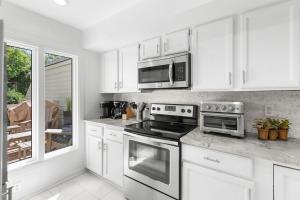 a kitchen with white cabinets and a stove and microwave at 774 Spinnaker Beach House in Seabrook Island