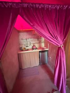 a kitchen with a pink curtain in a room at Ez-zine Glam in El Aadamna