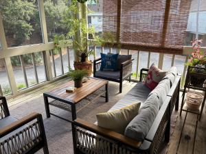 a screened in porch with a couch and chairs at 767 Spinnaker Beach House in Seabrook Island