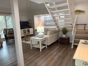 a living room with a couch and a spiral staircase at 767 Spinnaker Beach House in Seabrook Island
