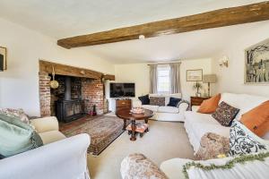 a living room with white furniture and a fireplace at Cutbush Farmhouse in Norwich