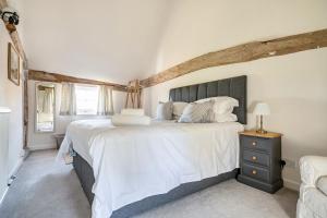 a bedroom with a large bed with white sheets at Cutbush Farmhouse in Norwich