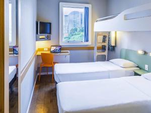 a hospital room with two beds and a desk with a laptop at ibis budget Rio de Janeiro Centro in Rio de Janeiro
