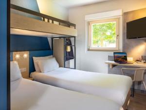 a bedroom with two beds and a desk and a bunk bed at ibis budget Bourg en Bresse in Bourg-en-Bresse