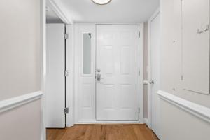 an empty hallway with a white door and wooden floors at 2943 Atrium Villa in Seabrook Island