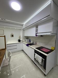 a kitchen with white cabinets and a table and a chair at Escapade urbaine moderne in Sétif