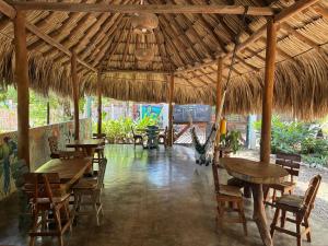 a restaurant with tables and chairs and a straw umbrella at Hostal El Bohío in Palomino