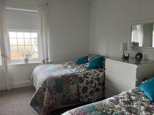 a bedroom with two beds and a dresser and a mirror at Stunning coastal cottage in Worle