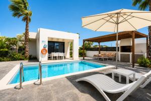 a villa with a swimming pool and an umbrella at Villa Salty Sun 4 in Kremasti