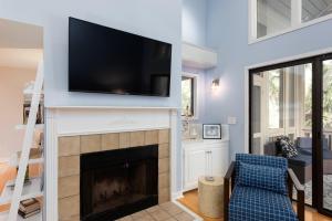 a living room with a fireplace with a flat screen tv above it at 2766 Live Oak Villa in Seabrook Island +38 photos
