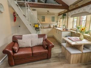 a living room with a leather couch and a table at Riverview Cottage in Holmfirth