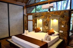 a bedroom with a large bed in a stone wall at Kottawatta Village in Udawalawe