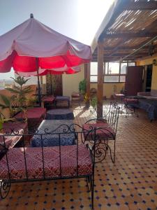 a patio with tables and chairs and an umbrella at Riad Andalousse in Meknès