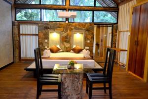 a bedroom with a bed and a table and chairs at Kottawatta Village in Udawalawe