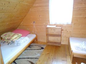 a room with two beds in a wooden cabin at Domek Bieszczady Wolkowyja 2 nad Solina in Wołkowyja