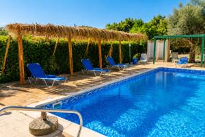 a swimming pool with blue chairs and a thatch roof at Amalia Apartments in Polis Chrysochous