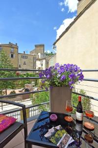 a table with a bottle of wine and flowers on a balcony at L'AMARILYS chambre d'hôte au coeur du village, terrasse avec vue sur le château in Châteauneuf-du-Pape
