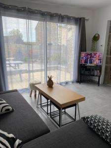 a living room with a table and a tv at Gite du Becquet in Le Rozel