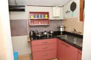 a kitchen with red cabinets and a sink at sunshine retreat in Coonoor