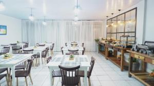a restaurant with white tables and chairs and a kitchen at Hotel LF By Feliciano in Barracão