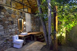 a stone bathroom with a sink and a toilet at Kottawatta Village in Udawalawe