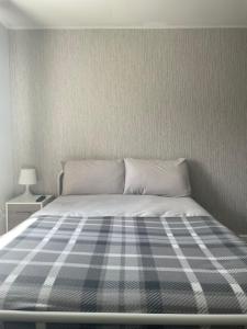 a bed with a blue and white plaid blanket on it at Jayden house in Middlesbrough