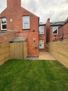 a brick house with a wooden fence in the yard at The Lenton House in Nottingham