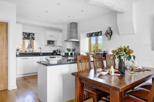 a white kitchen with a wooden table and chairs at Pitstop in Dartmouth