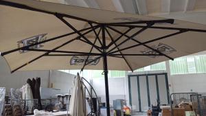 a large umbrella in a room with tables and chairs at Le colline in corso Bra in Alba