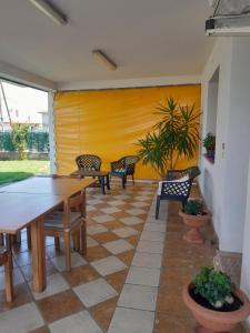 a patio with tables and chairs and a yellow wall at Casa Cristina in Ospedaletto Euganeo