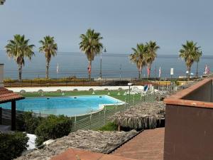 a swimming pool next to the ocean with palm trees at Effegi Casa Vacanze in Mandatoriccio Marina