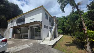 a white house with a car parked in front of it at Villa El Gato in Bouillante