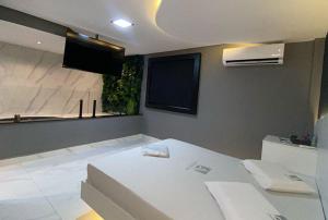 a room with a white bed and a flat screen tv at Anonimato Hotel in Santos +3 photos