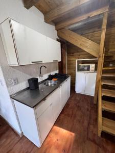 a kitchen with white cabinets and a sink at Cabanas da zimba in Imbituba +5 photos