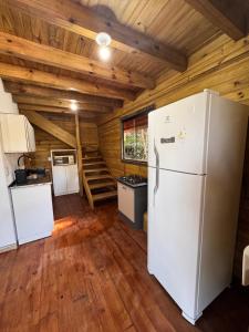 a kitchen with a refrigerator in a room with wooden ceilings at Cabanas da zimba in Imbituba