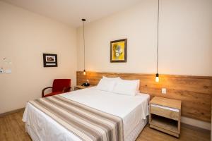 a bedroom with a white bed and a red chair at Rancho das Pedras Itaberá in Itaberá +41 photos