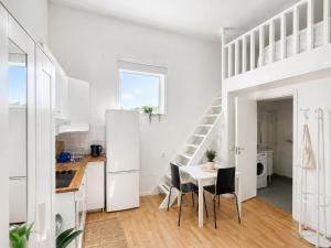 a white kitchen with a table and chairs and a staircase at Cozy Cottage in Södertälje