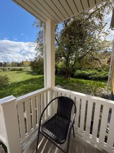 a black chair sitting on a porch looking out at a yard at Cozy Cottage in Södertälje +8 photos