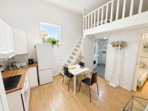 a white kitchen with a table and a loft bed at Cozy Cottage in Södertälje