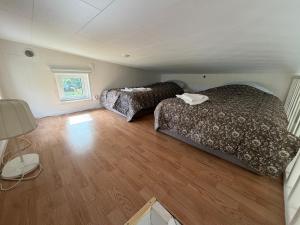 a small bedroom with two beds and a wooden floor at Cozy Cottage in Södertälje