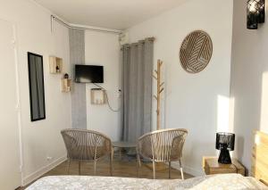 a bedroom with chairs and a table and a tv at Le Minimaliste Chic in Montbrison
